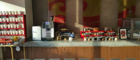 Un coin cuisine équipé d’une machine à café, d’un réfrigérateur et de divers ustensiles de cuisine.
