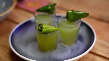 Un tazón con tres vasos de líquido verde, cada uno adornado con un chile verde.