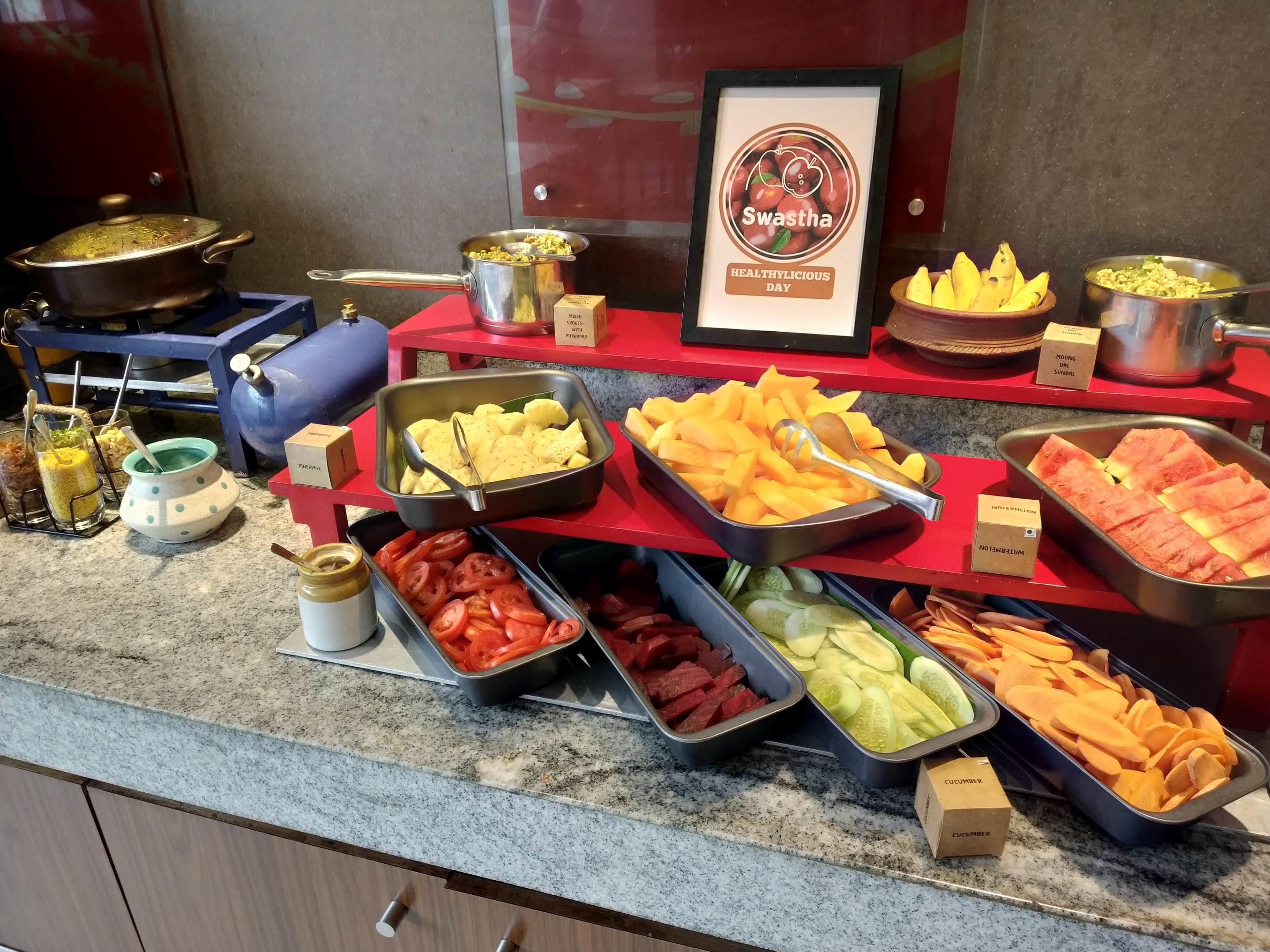 A buffet with various food items including fruits, vegetables, and sauces.