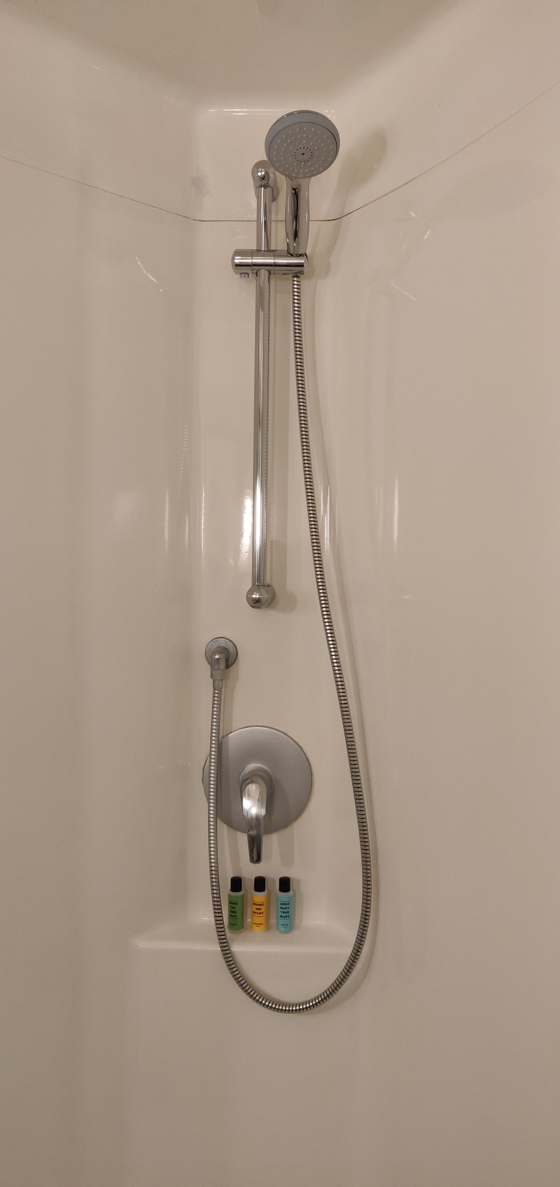 A shower with a handheld showerhead and a fixed showerhead, a handheld shower hose, and a control knob.
