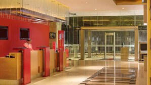 Zona de recepción de un hotel con diseño moderno, que incluye un mostrador de recepción, una entrada de cristal y un mostrador de registro.