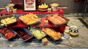 Un bufé con diversas frutas y verduras, entre ellas sandía, melón y pepinos.