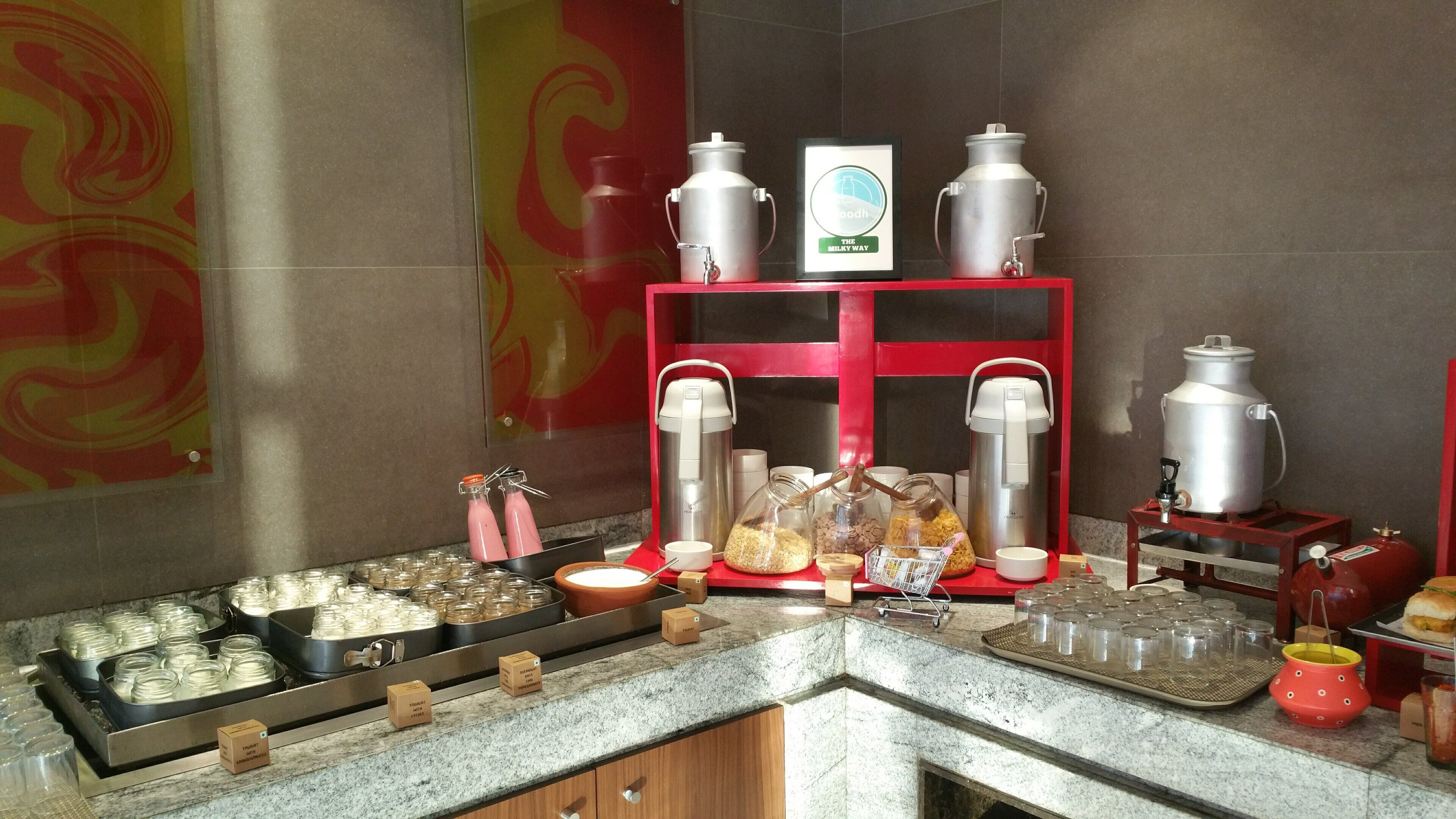 A buffet setup with various food containers, a coffee station, and a beverage dispenser.