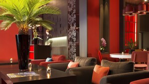Een moderne lobby met een receptiebalie, een zithoek en een grote potplant.