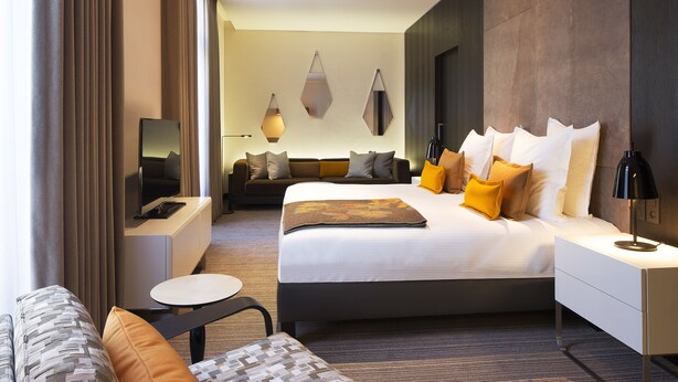 Een moderne hotelkamer met een groot bed, een bank, een klein tafeltje en een televisie.