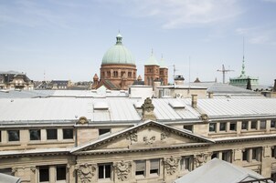Um edifício histórico com uma cúpula imponente e cúpulas menores, rodeado por outros edifícios com telhados planos.