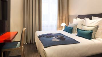 A hotel room with a bed, a desk, and a chair.