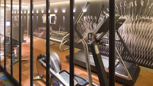 Een sportschool met diverse fitnessapparaten, waaronder loopbanden en elliptische trainers, in een ruime opstelling.