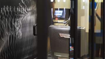 A view through a glass door with a reflection of a room containing a desk and a computer.