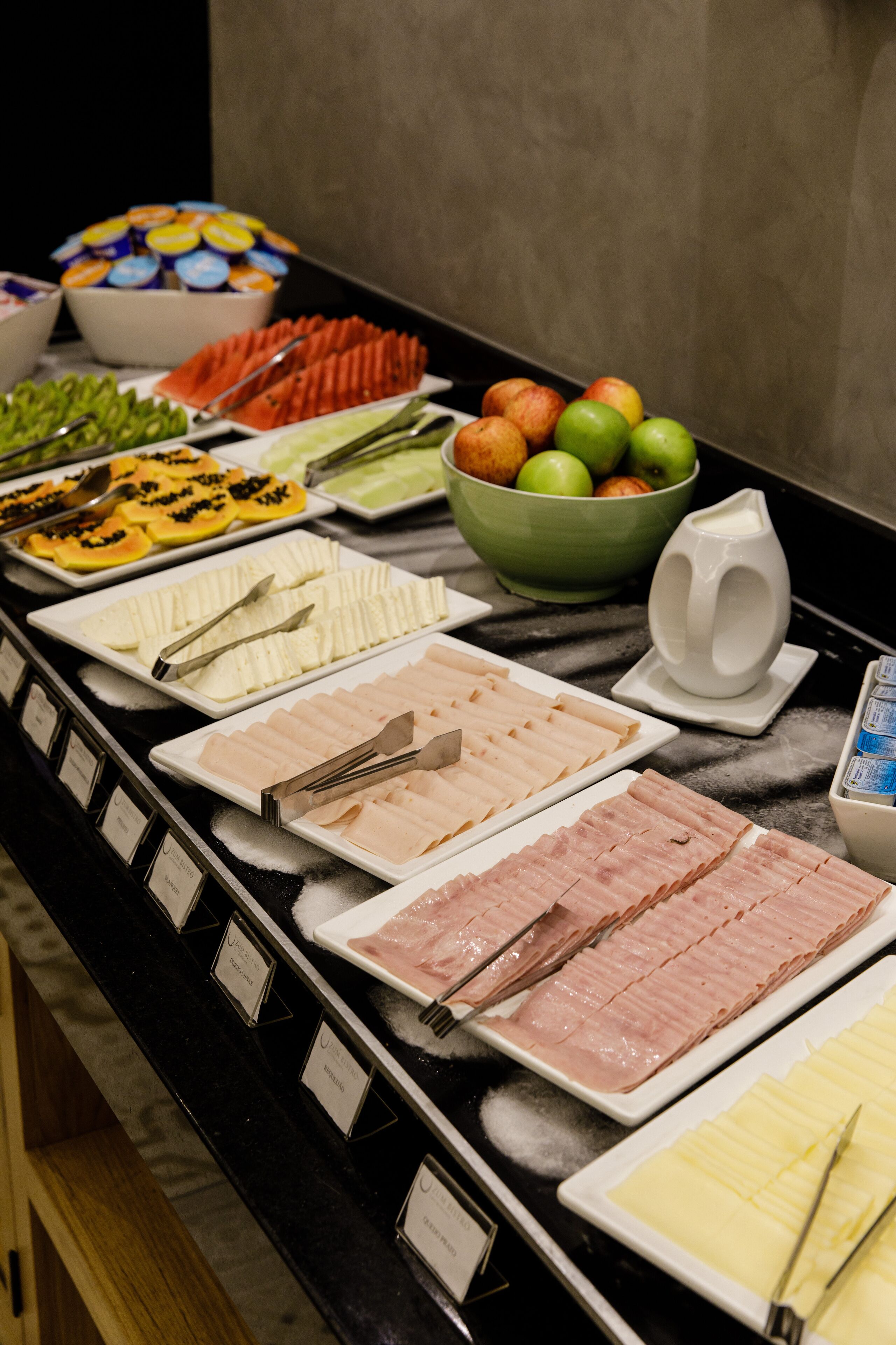 Un bufé con diversas opciones de comida, incluyendo carnes, frutas y verduras.
