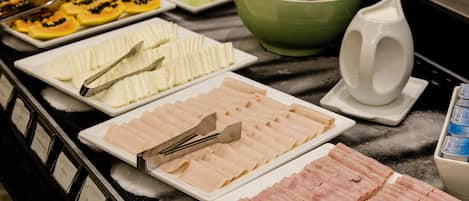 Un bufé con diversas opciones de comida, incluyendo carnes, frutas y verduras.