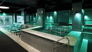 Zona de piscina con sillones de descanso y un muro de azulejos.