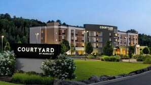 A Courtyard by Marriott hotel with a modern design, featuring multiple floors and a well-maintained lawn area.