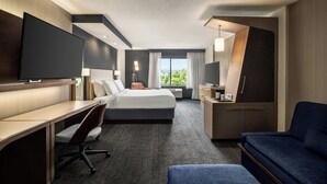 A modern hotel room with a large bed, a desk, a flat-screen TV, and a sofa.