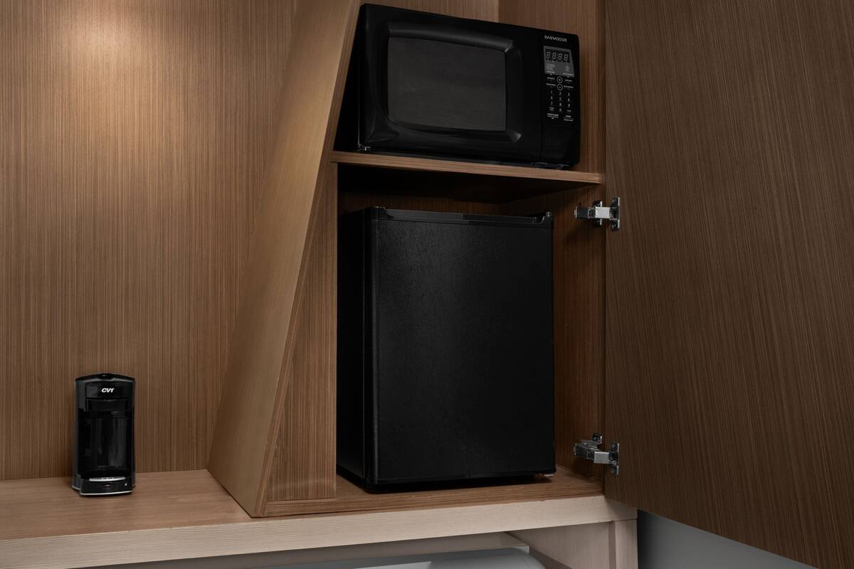 A kitchen cabinet with a microwave and a coffee maker.