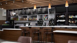 A modern bar area with wooden ceiling, bar stools, a coffee machine, and shelves stocked with bottles. - Courtyard Philadelphia Bensalem (Bensalem)