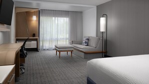 A modern hotel room with a bed, a sofa, a desk, and a TV. - Courtyard Philadelphia Bensalem (Bensalem)