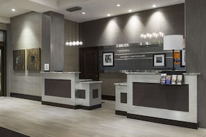 Welcome to our reception area, featuring two desks with digital screens and a unique textured pattern on the walls.