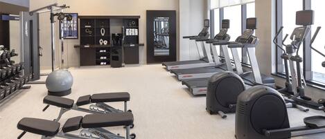 Une salle de sport équipée de tapis de course, de vélos elliptiques et de poids libres.