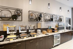 A buffet setup with various food stations, including trays of eggs, meats, and salads.
