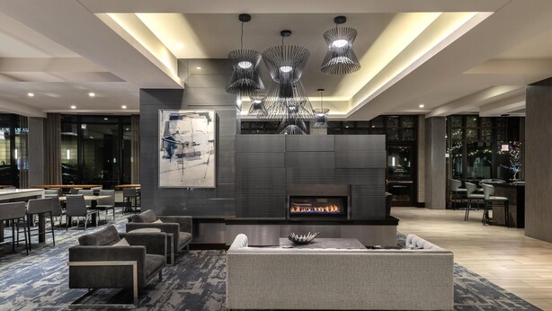A modern lounge area with a fireplace, sofas, and a dining area.