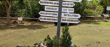 A directional signpost with multiple arrows pointing in different directions, surrounded by rocks and greenery.