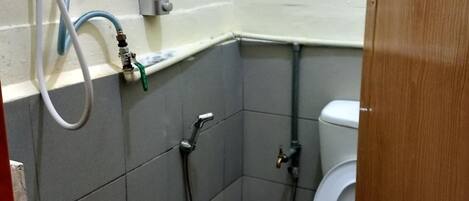 A small, tiled bathroom with a toilet, a shower, and a water heater.