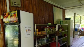 Una habitación con refrigerador, congelador y estantes repletos de diversos alimentos.