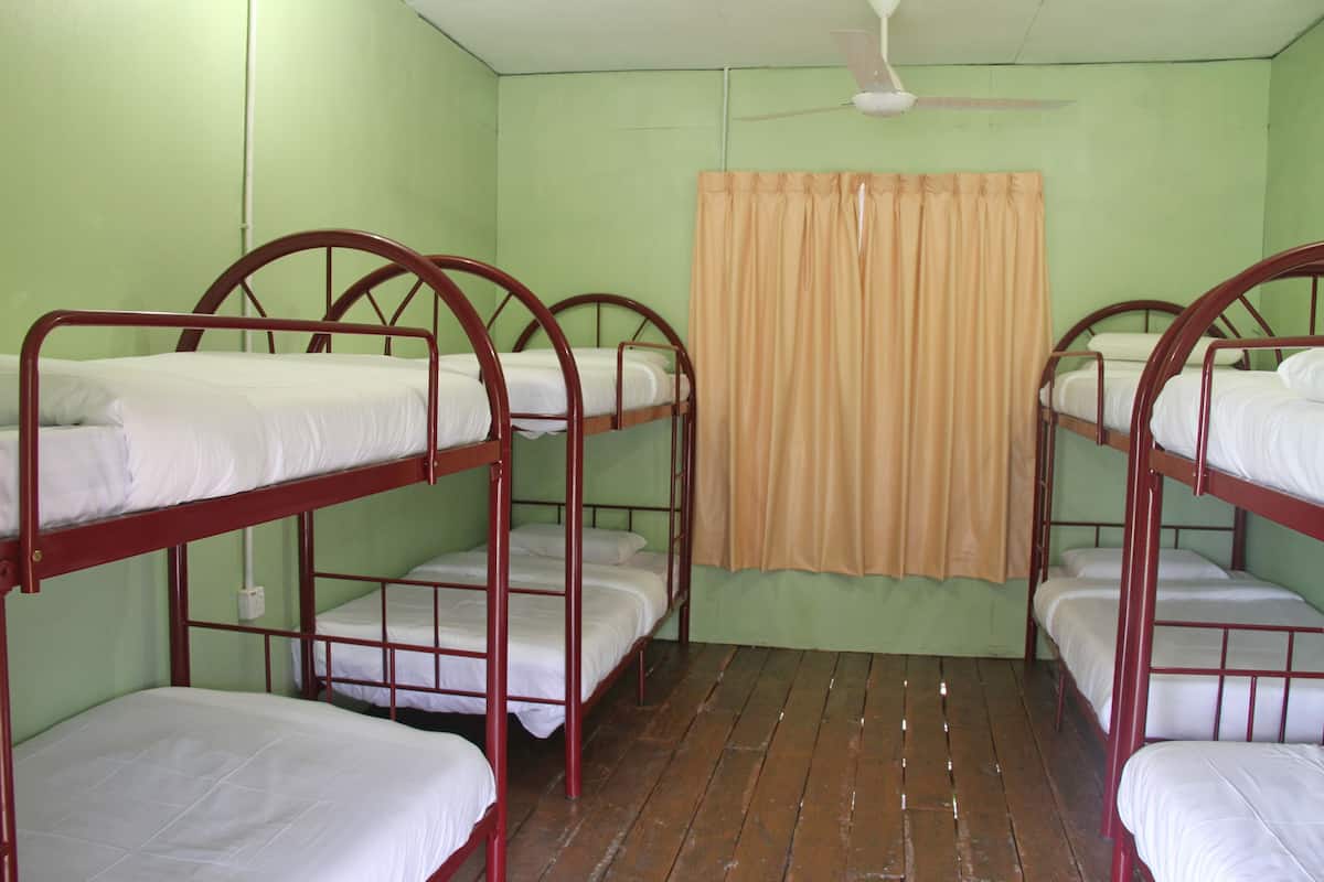 A dormitory room with bunk beds, a ceiling fan, and a curtain.