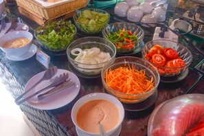 Una mesa de buffet con diversos platos, incluyendo ensaladas, verduras y un bol de sopa.