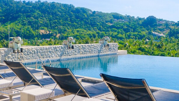 A pool with lounge chairs and stone statues on a terrace overlooking a lush green hillside. - YouDee Hotel Patong (formerly Meir Jarr Hotel) (Patong)