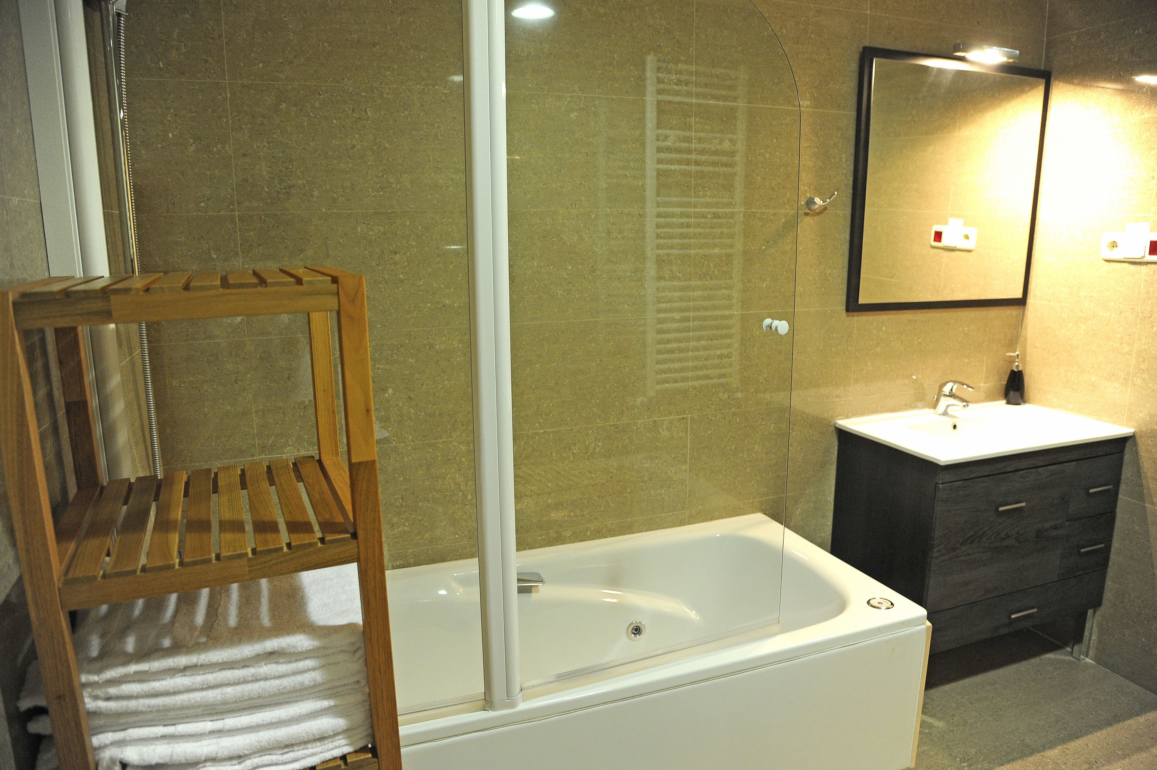 A bathroom with a bathtub, a wooden towel rack, a sink, and a mirror.