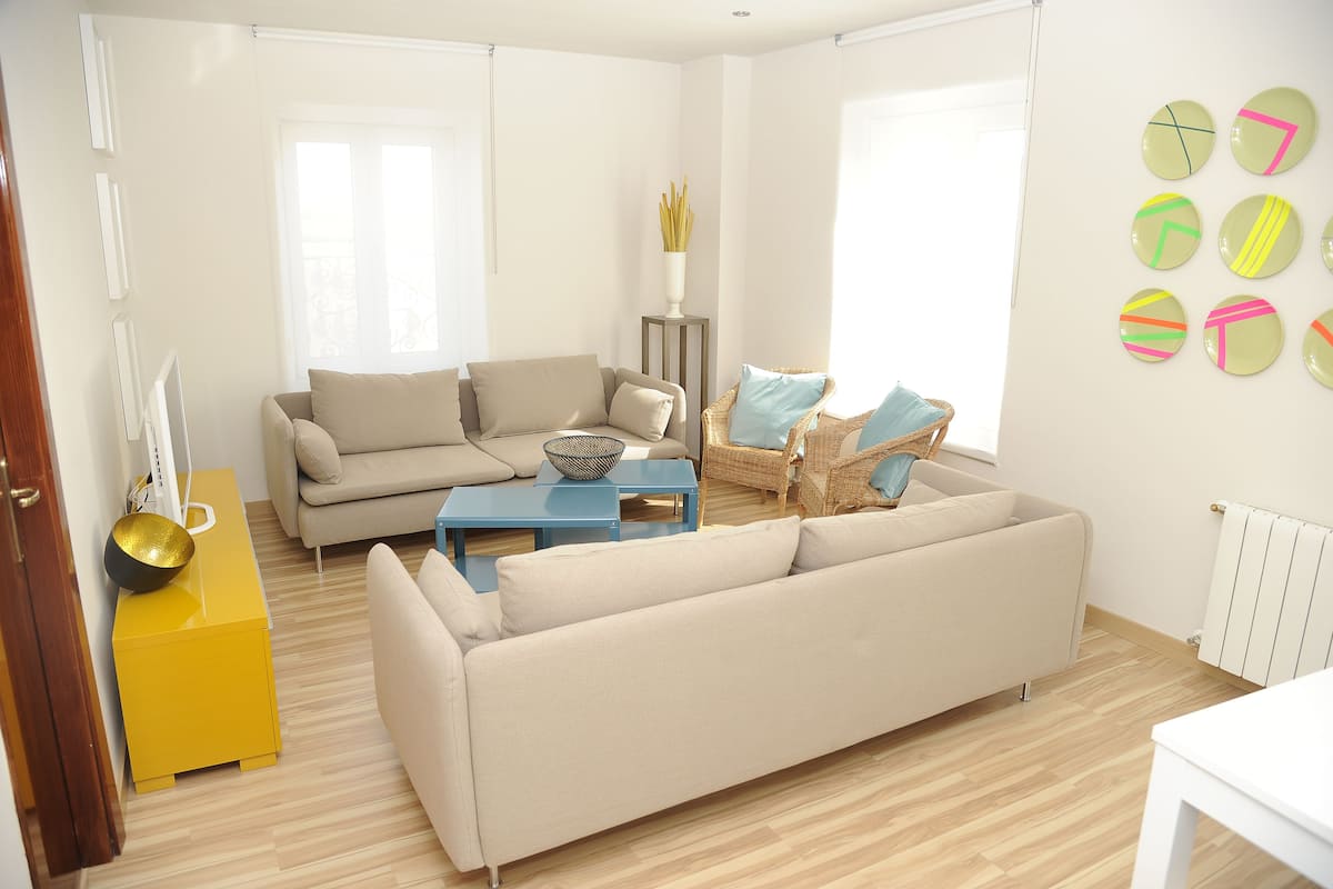 A modern living room with a beige sofa, a blue coffee table, and a yellow side table.