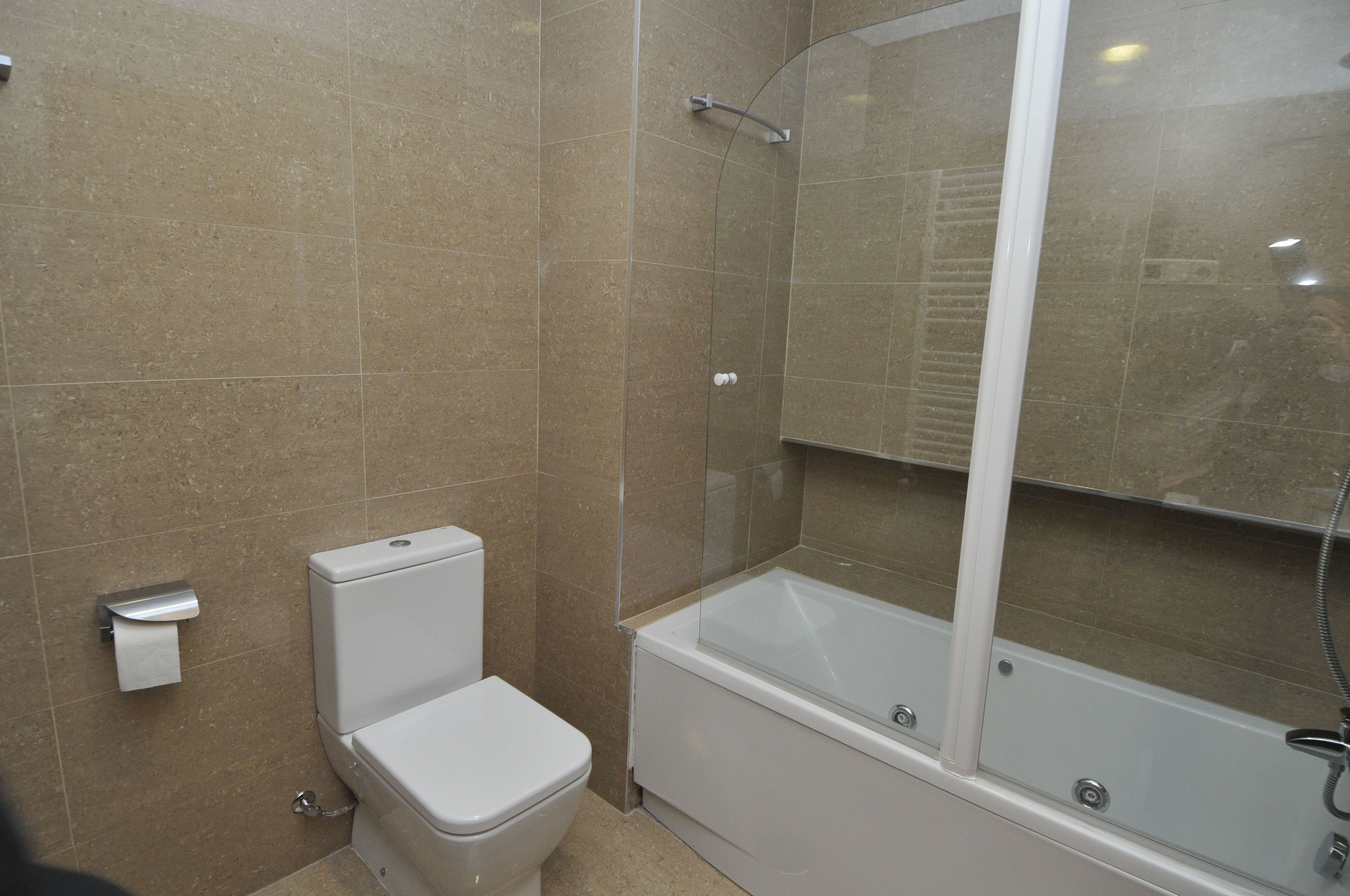 A bathroom with a toilet, a bathtub, and a glass-enclosed shower.