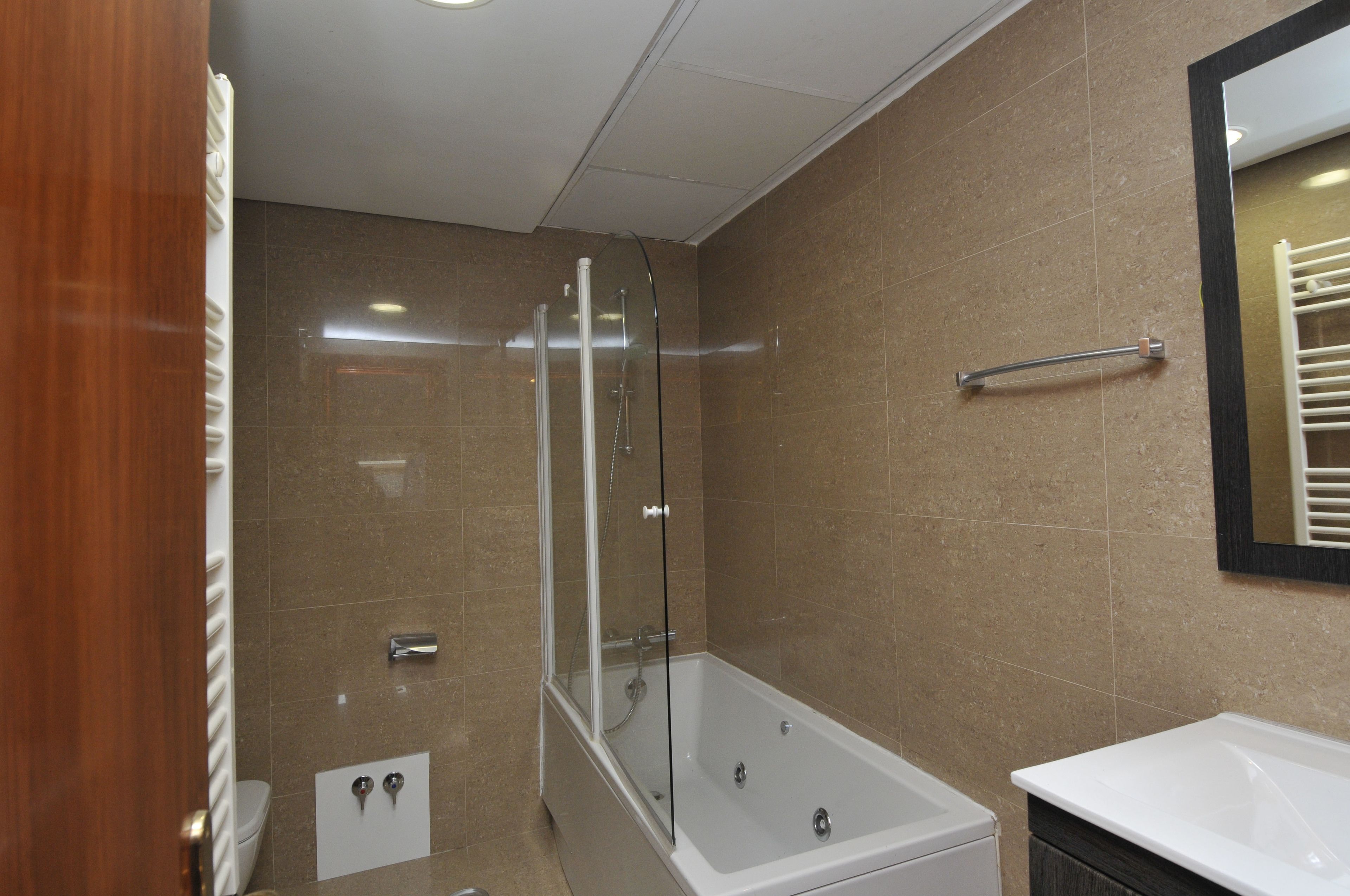 Une salle de bain moderne dotée d’une douche à parois de verre, d’une baignoire sur pieds et d’un meuble-lavabo avec un miroir.