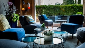 Ein moderner Außenbereich mit blauen Sofas, runden Tischen und einem Blumentopf.