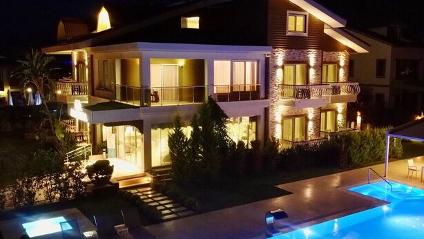 A two-story house with a swimming pool, outdoor lighting, and a balcony.