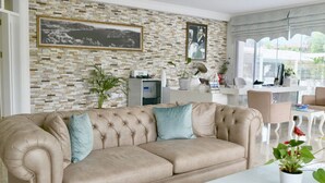 A living room with a beige sofa, a white coffee table, and a brick-patterned wall.