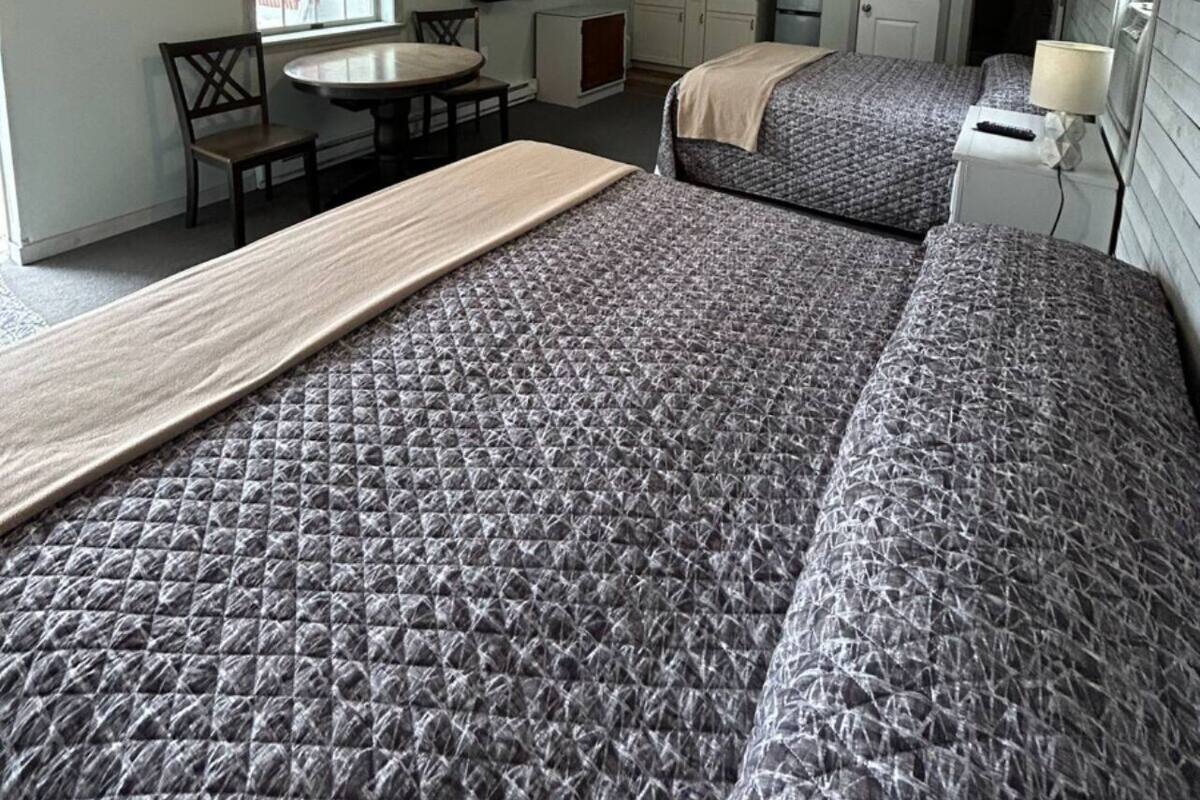 A compact room with two beds, a small kitchenette, a dining area, and a television.