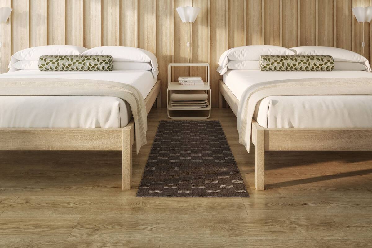 Quarto com duas camas, uma mesinha de cabeceira, um lustre e parede estampada.