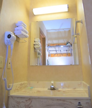 Un baño con lavabo, espejo, toallero y secador de pelo.