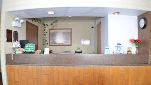 A reception desk with a wooden finish, a framed picture on the wall, and a clock. - Old Towne Motel (Westby)
