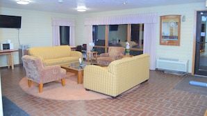 A living room with two sofas, a coffee table, and a television. - Old Towne Motel (Westby)