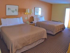 Una habitación de hotel con dos camas, un teléfono y una lámpara.