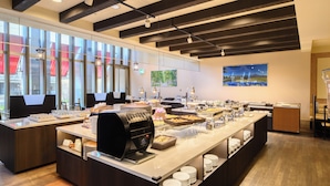 A modern kitchen with a buffet setup, including a coffee machine, food display, and seating area. - Hotel Lifort Sapporo (Sapporo)