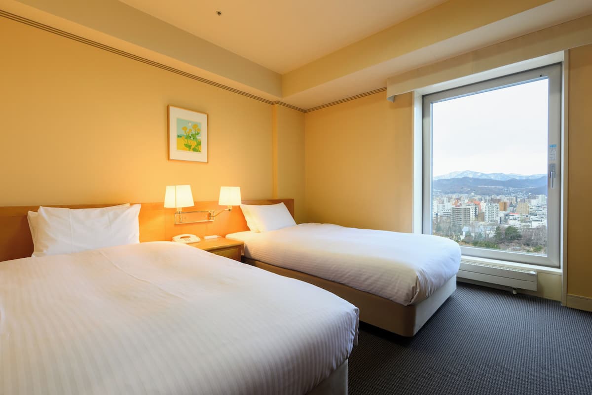 Una habitación de hotel con dos camas, vistas a la ciudad y un cuadro en la pared.