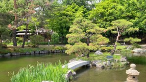 A serene garden with a stone bridge, a pond, and traditional Japanese landscaping. - Hotel Lifort Sapporo (Sapporo)