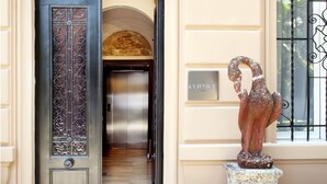 An entrance with a black door, a staircase, and a statue.