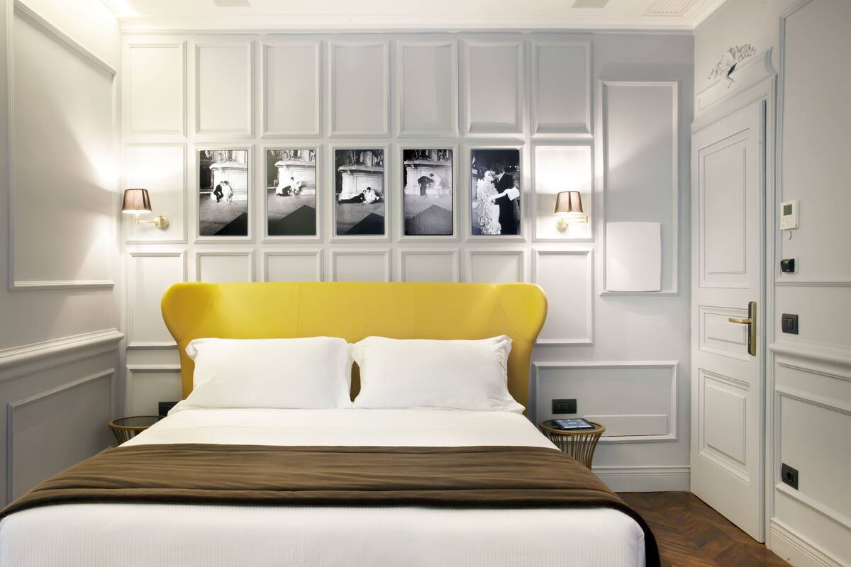 Une chambre d’hôtel avec un grand lit, une tête de lit, un mur décoré de photos et une table de chevet.