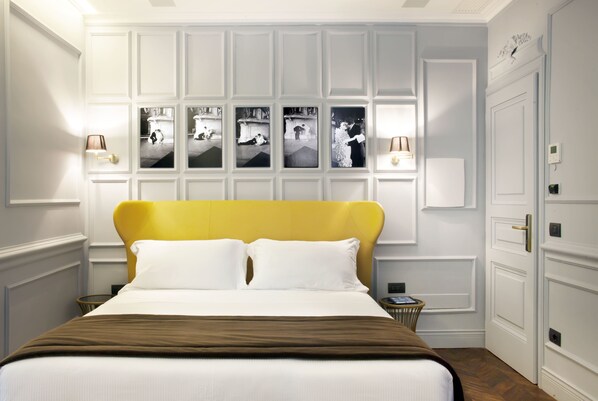 Quarto de hotel com uma cama grande, cabeceira, painel de fotos fixado na parede e mesa de cabeceira.